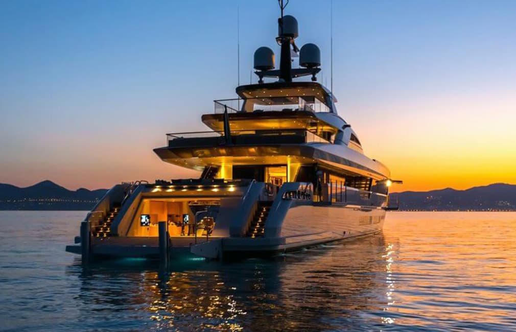 Luxurious yacht standing still on a water in the sunset and hills in the background