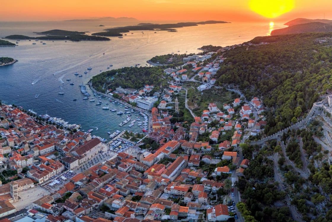 Aerial shot of a coastal town in the sunset with many boats on the water