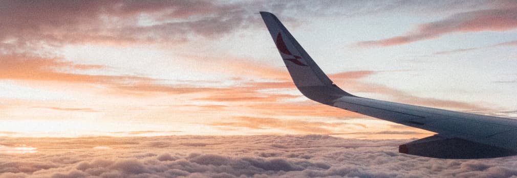 View of clouds and sky in the sunset with airplane wing in the focus