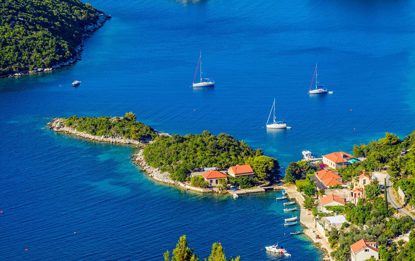 Couple of boats sailing on a deep blue water with small coastal town in front