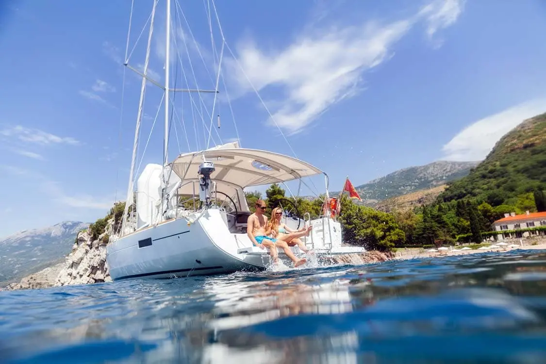 Family sitting at the edge of a boat with their feet in the sea