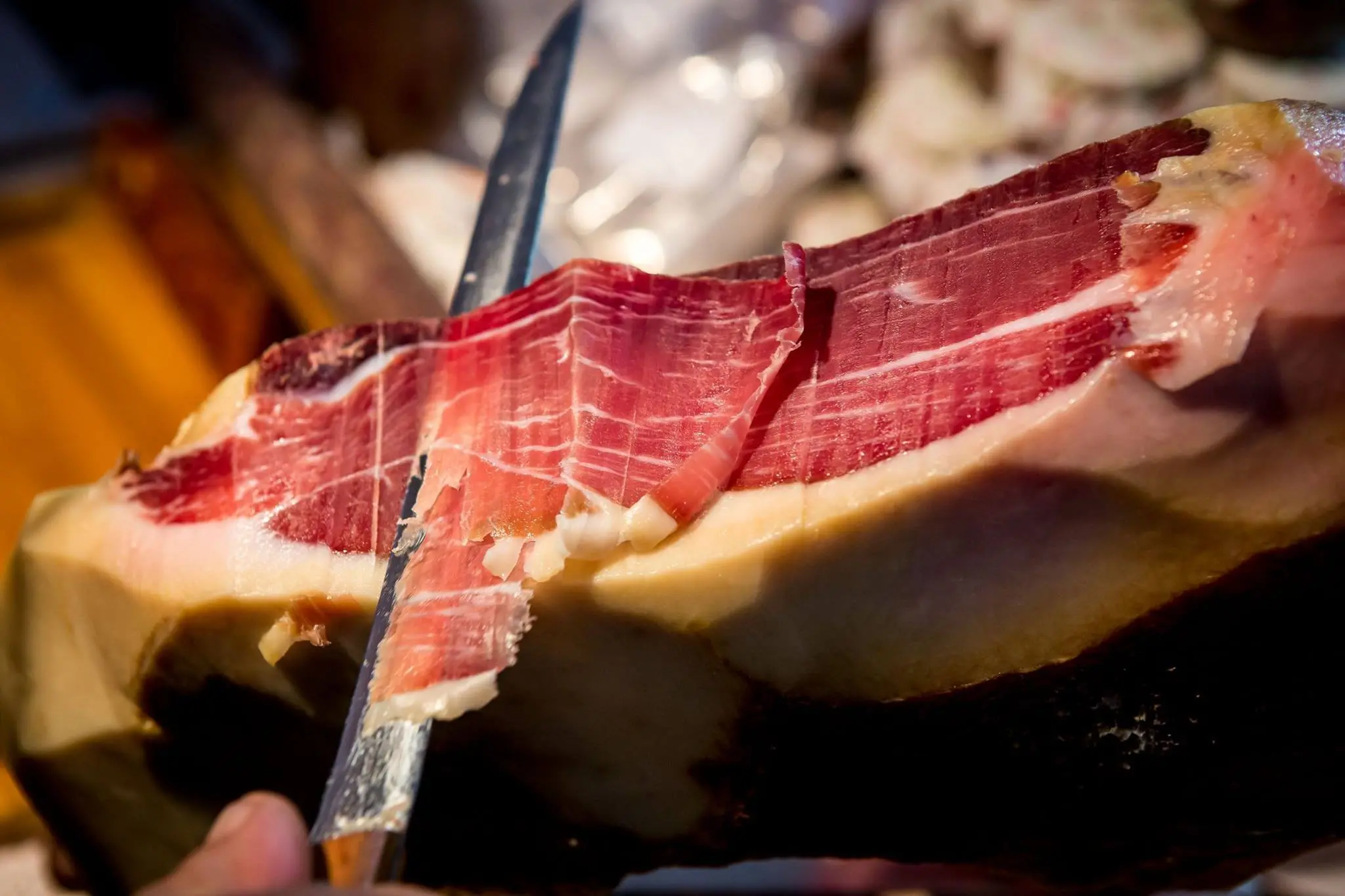 Prosciutto being cut into thin slices