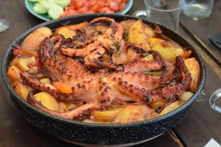 Octopus served in a dish with salad on the side